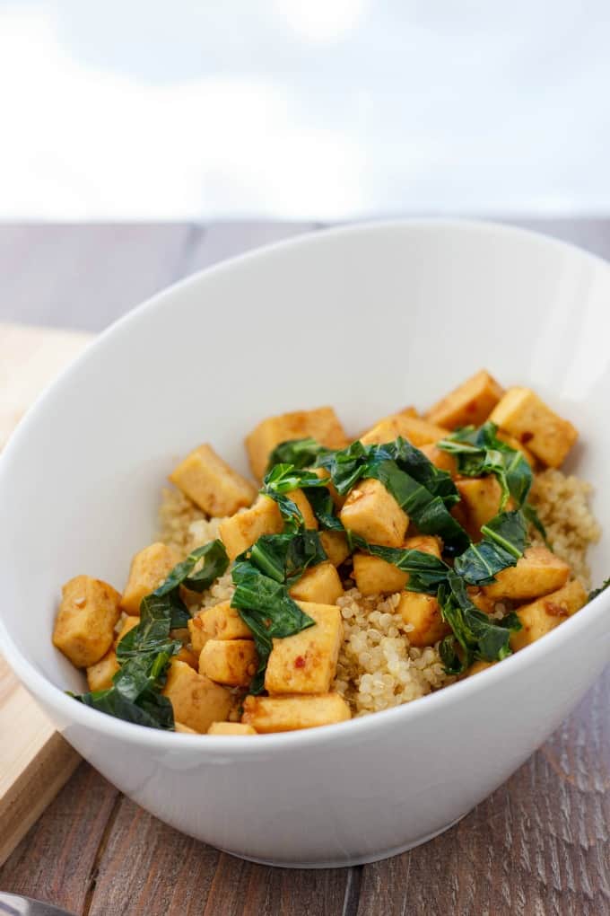 Sweet and Tangy Tofu with Greens over Quinoa in white bowl on table#tofu