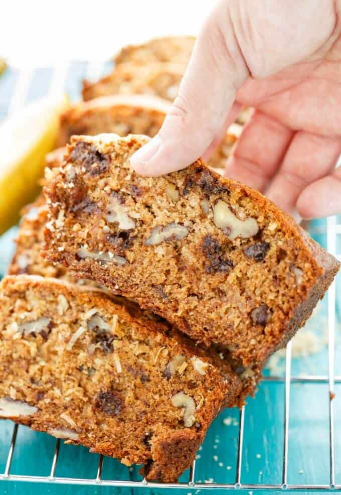 Chocolate Chip Banana Bread  slices held by hand with Coconut and Nuts on baking rack#bread