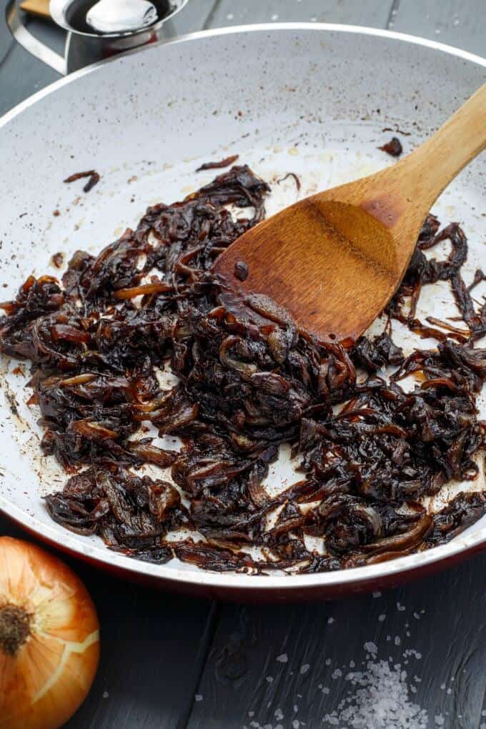 How to Caramelize Onions - Caramelized onion in pan with wooden spatula