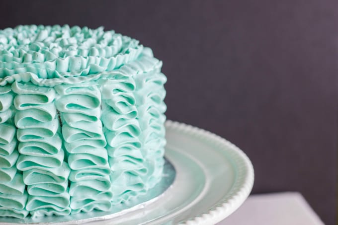 Swiss Meringue Buttercream Ribbon Cake on white plate, gray background