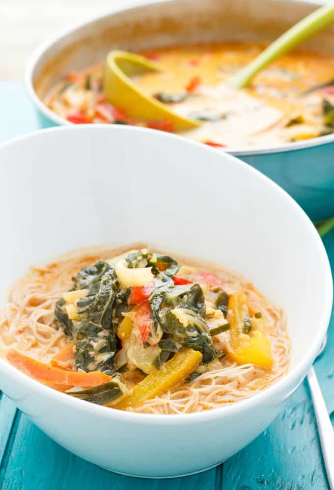 Coconut Curry Soup over Vermicelli Rice Noodles  in white bowl on blue table, pot with soup in the background#soup