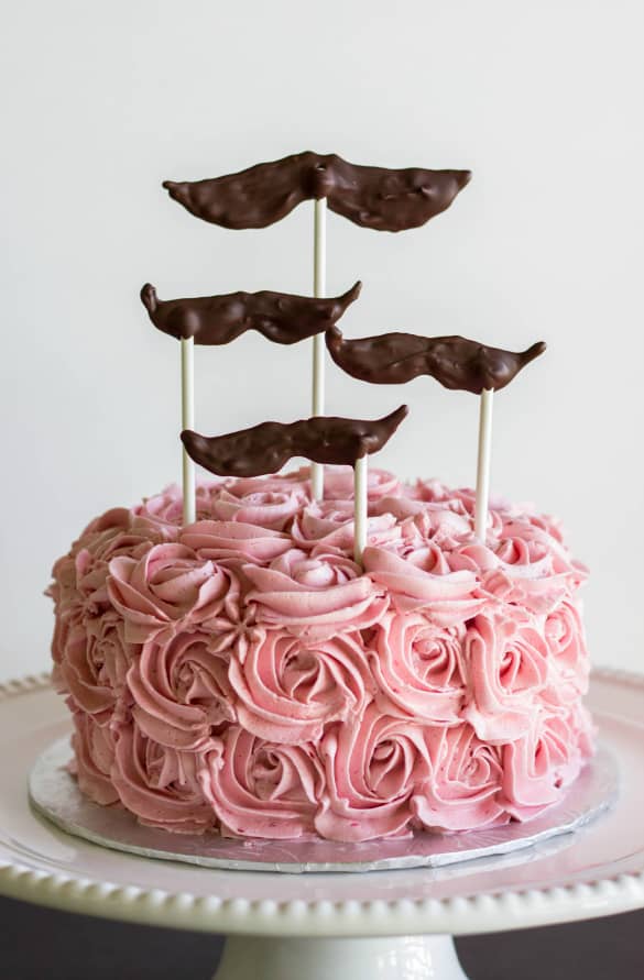 Pink cake with chocolate accesories on white stray