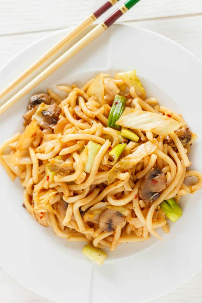 Fried Udon Noodles with Mushrooms and Cabbage on white plate and sticks