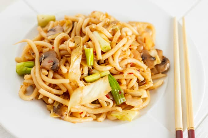 Fried Udon Noodles with Mushrooms and Cabbage on white plate and sticks