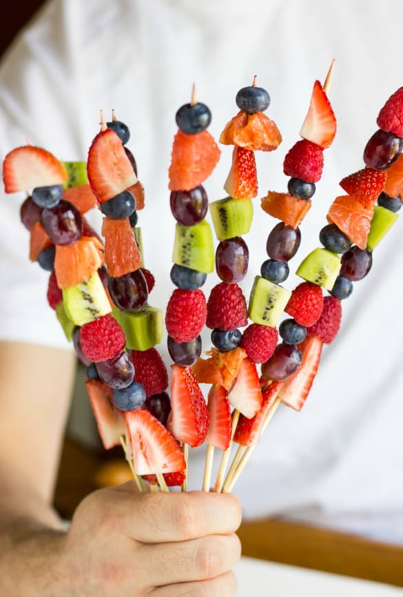 Man holding fruit kabobs 