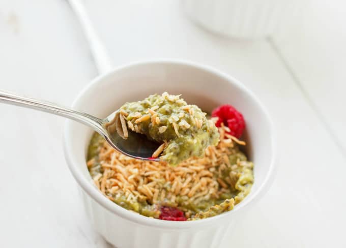 Vegan Green Tea Chia Seed Pudding in white bowl with raspberries picked up by spoon