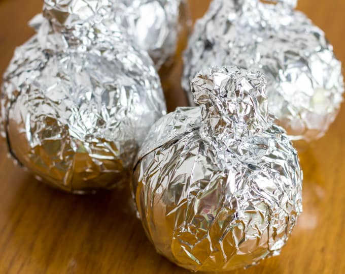 Baked Campfire Apples wrabed in bakeing foil on wooden table