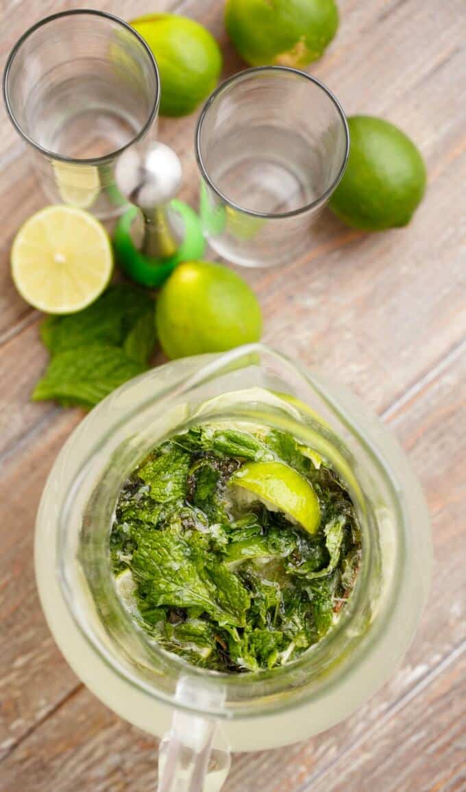 Half Pitcher of Mojitos in pitcher on table with sliced lemons#drink