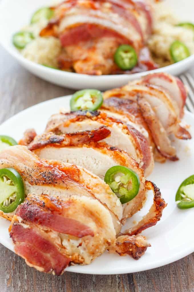 Jalapeno Popper Stuffed Chicken on white plate on wooden table#bacon