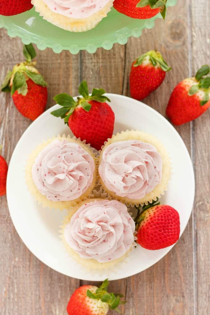 Lemon Cupcakes with Strawberry Swiss Meringue Buttercream on white plate and brown table next to ripe strawberries #strawberry