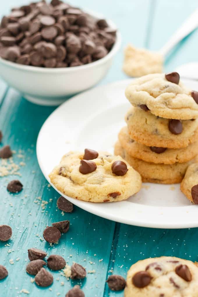 Soft and Chewy Chocolate Chip Cookies on white plate on blue table, nexto to chocolate chips and white bowl#chocolate