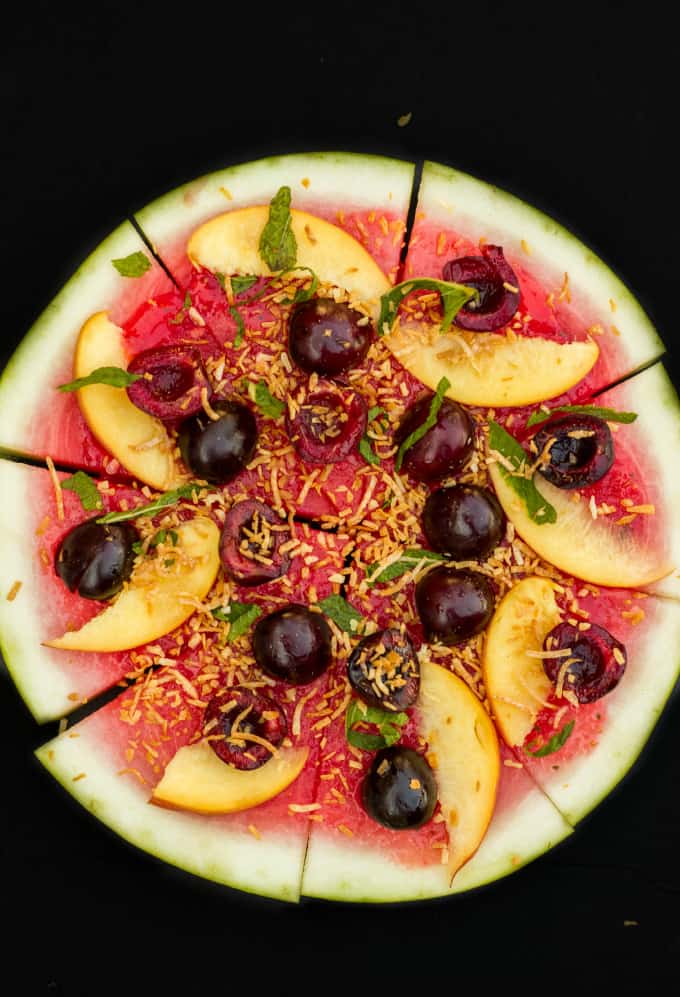 Healthy Vegan Watermelon Pizza Dessert sliced on black background