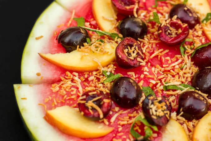 Healthy Vegan Watermelon Pizza Dessert sliced on black background