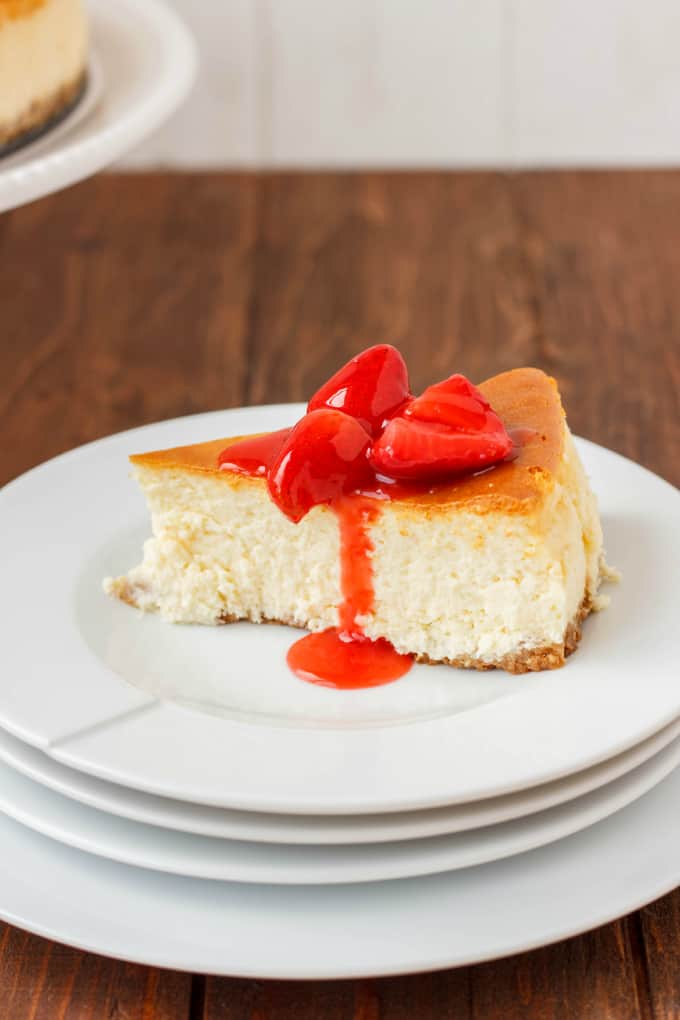 New York Style Cheesecake with Strawberry Topping on white plates on wooden table