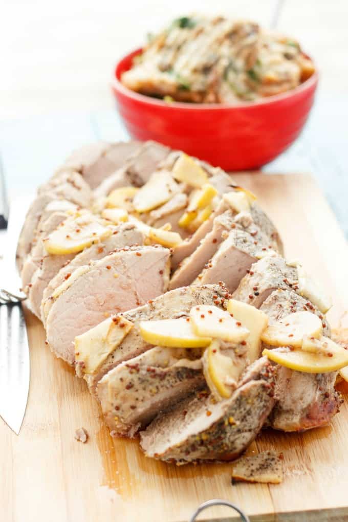 Pork Tenderloin in the Slow Cooker  sliced on wooden pad with knife, red bowl in the background#slowcooker