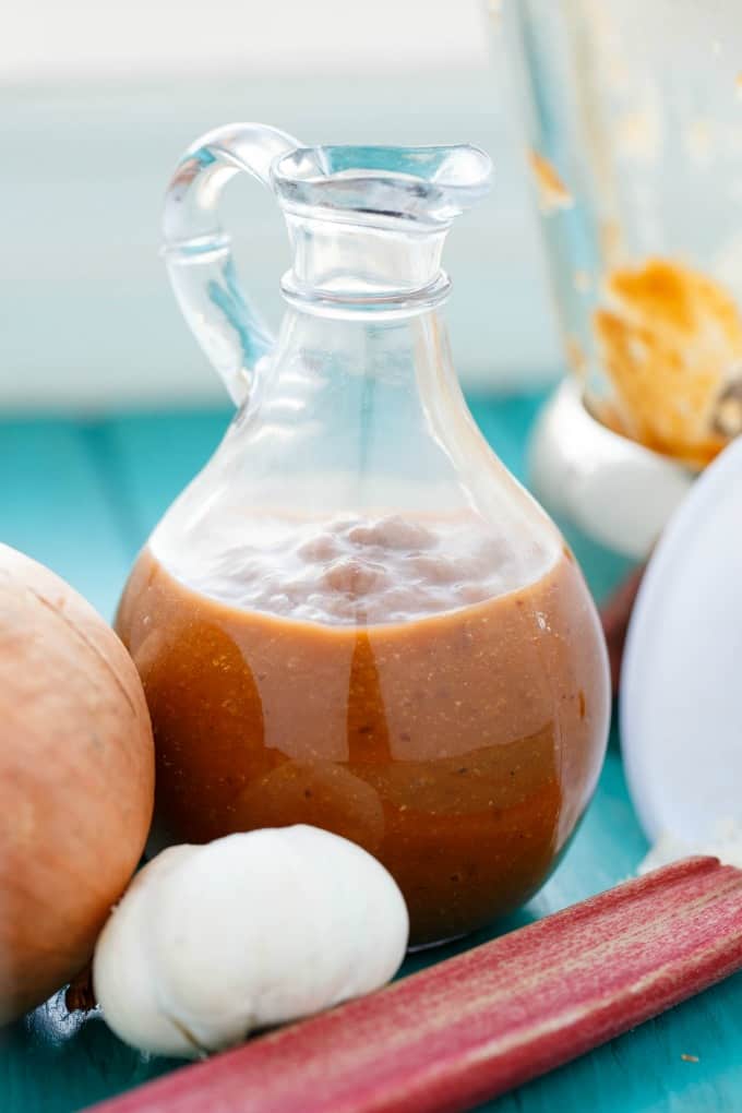 Rhubarb BBQ Sauce in glass jar on blue table enxt to veggies #sauce