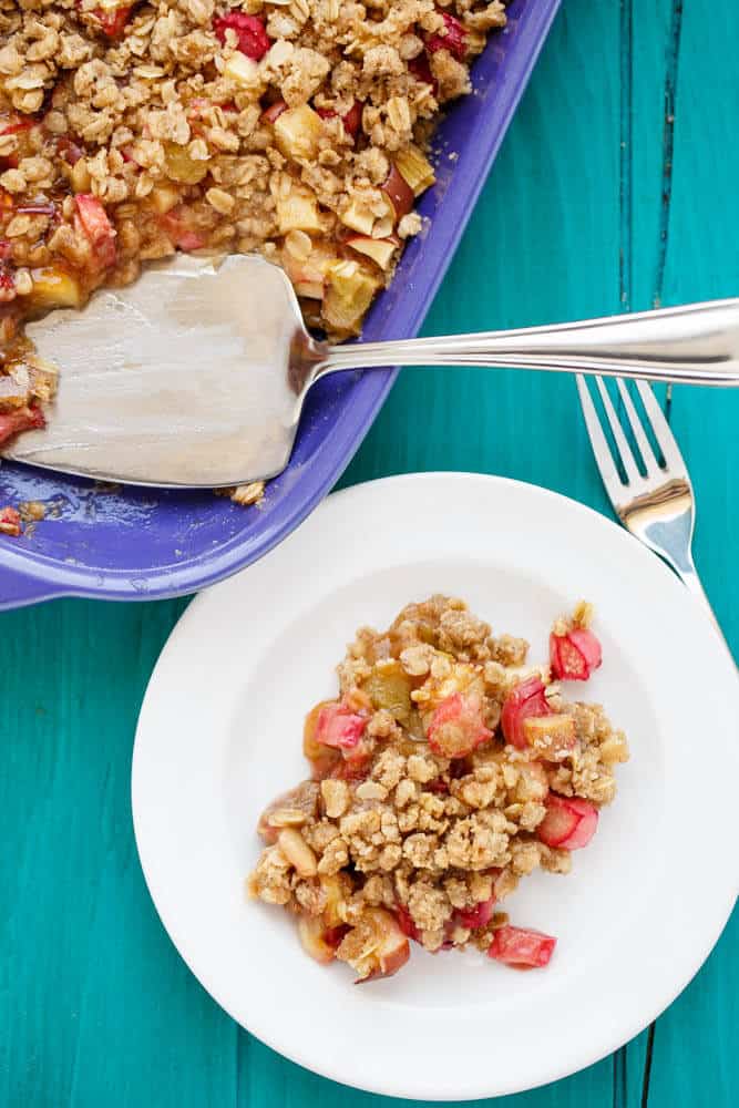 Rhubarb Crumble Brown Betty dessert on plate and big baking pan with spatula and fork on blue table#vegetarian