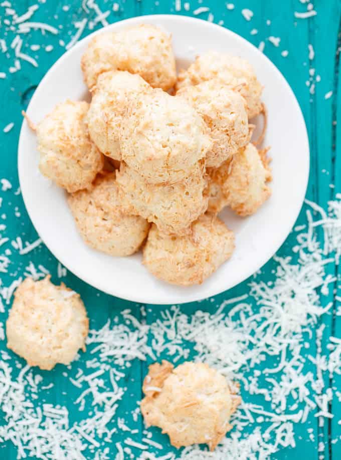 Semi-Toasted Coconut Macaroons on white plate on blue table sprinkled by sliced coconut#coconut