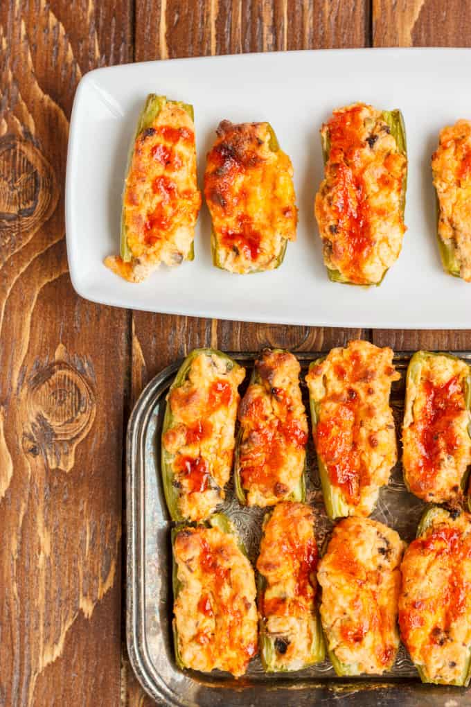 Mushroom and Cheese Stuffed Jalapenos on white and brown plates on wooden table