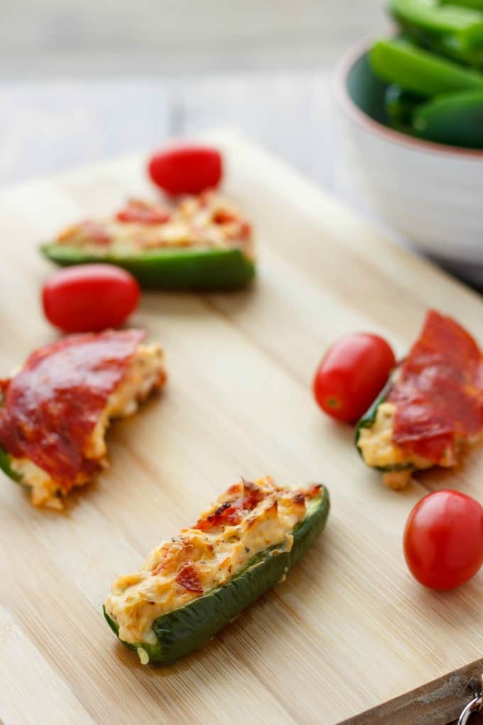 Pizza Stuffed Jalapenos on wooden kitchen pad with tomatoes #appetizer