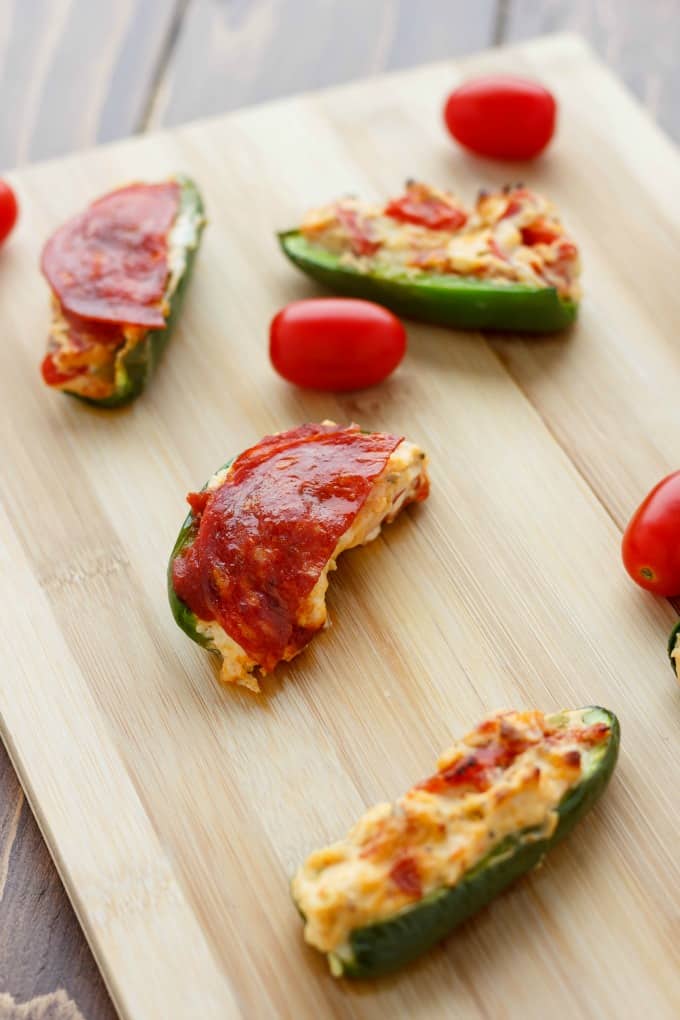 Pizza Stuffed Jalapenos on wooden kitchen pad with tomatoes#party