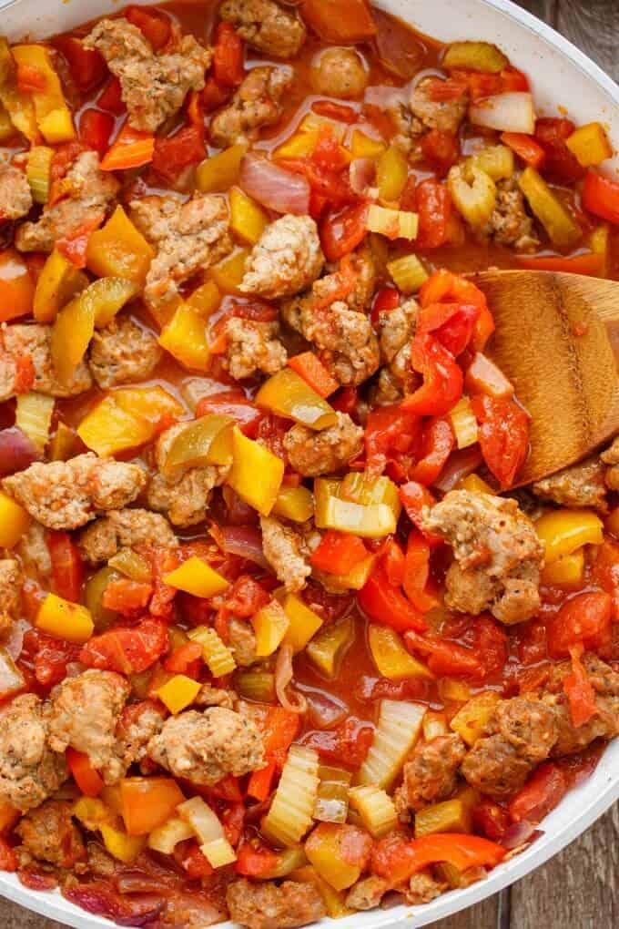 Sausage and Peppers over Rice  in white bowl with wooden spatula#sauce