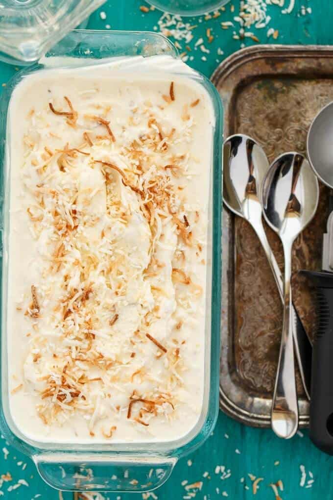 Toasted Coconut Ice Creamin glass jar on blue table next to spoons in baking pot #icecream