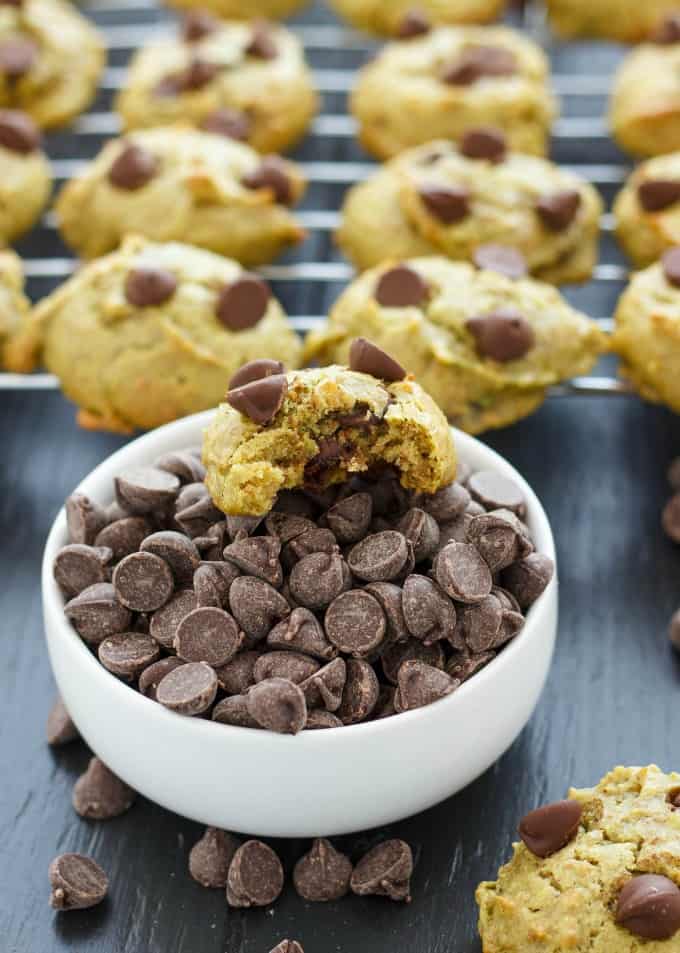 Avocado Chocolate Chip Cookies on black table with white bowl full of chocolate chips and half eaten cookie#chocolate