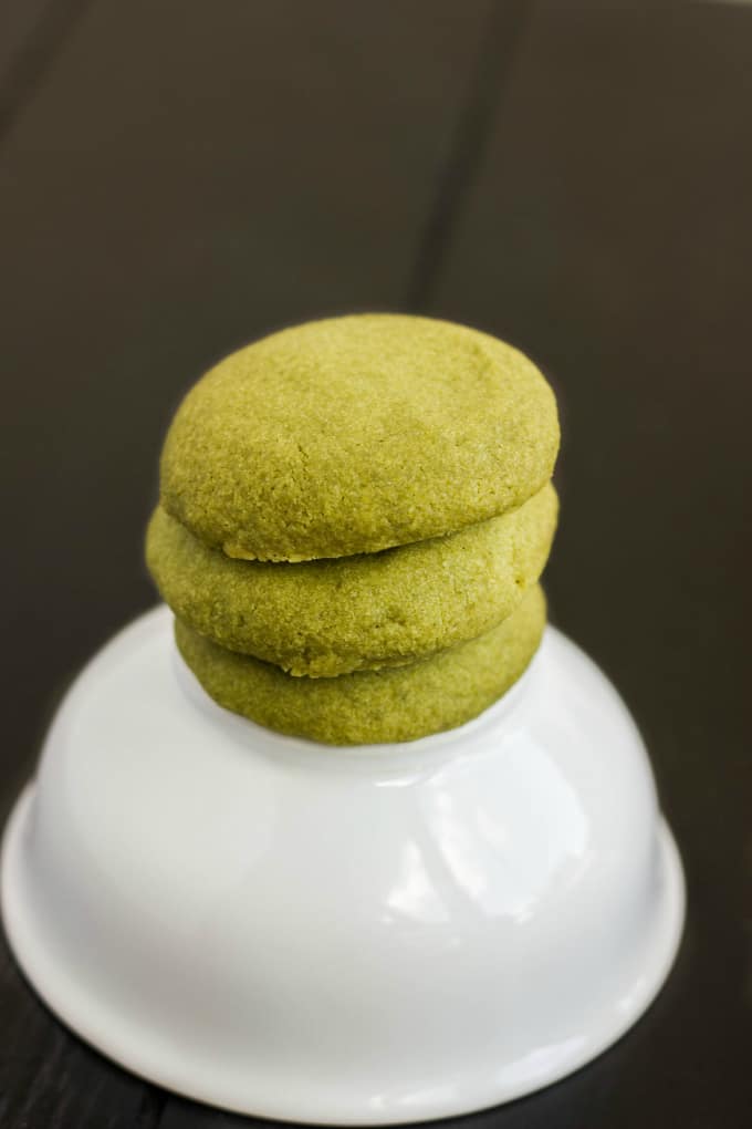 Matcha Green Tea Shortbread Cookies sitting on upsidewn white bowl on black table