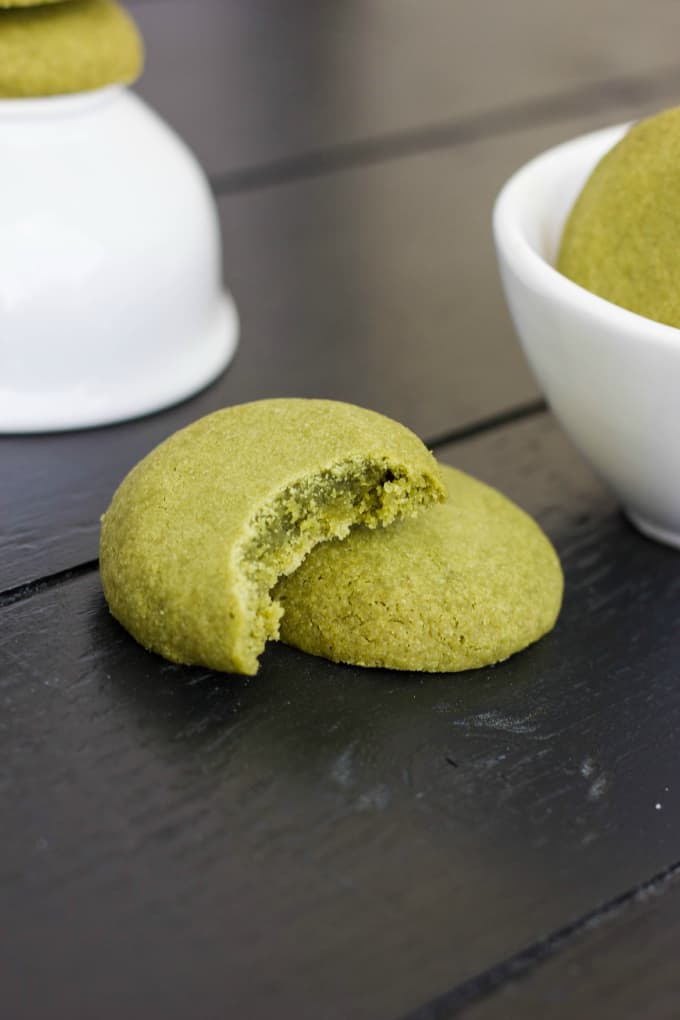 Matcha Green Tea Shortbread Cookies half eaten on black table, next to white bowls