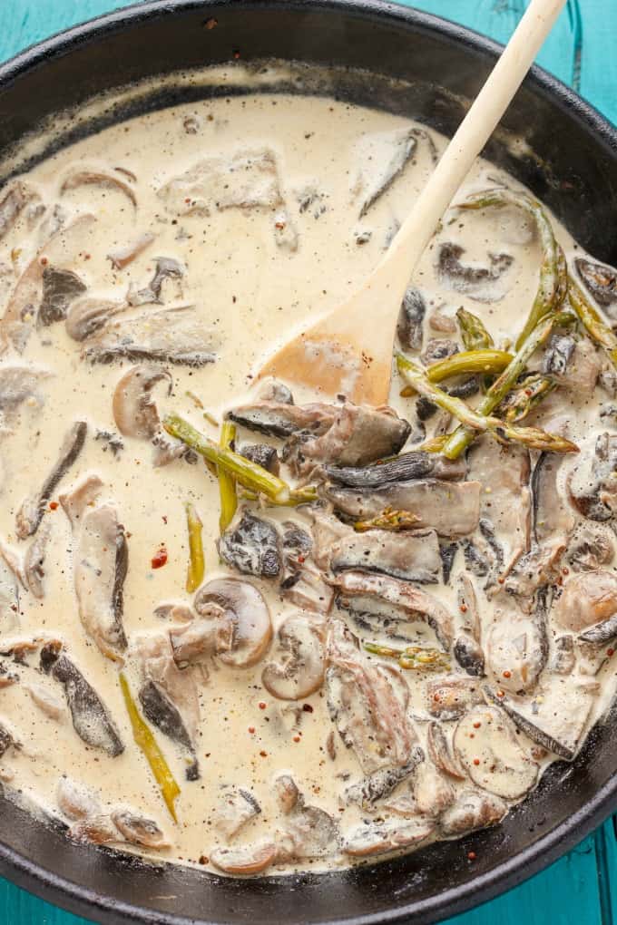 Portobello mushroom pasta with cream sauce in black pan with wooden spatula