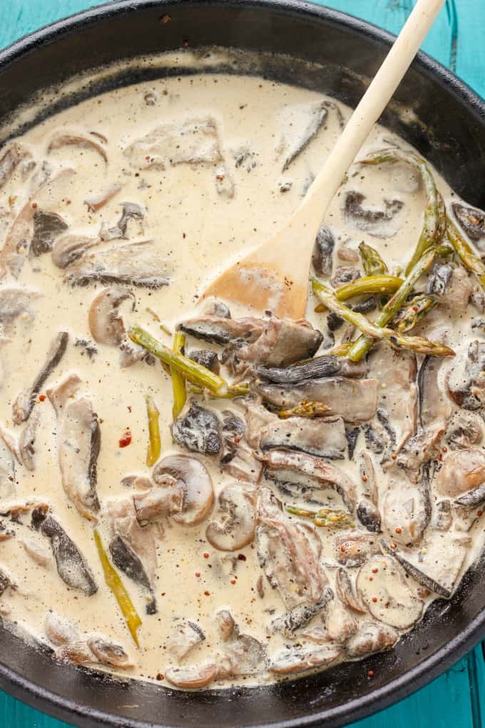 Portobello Mushroom Pasta with Cream Sauce #sauce in black pan with wooden spatula on blue table