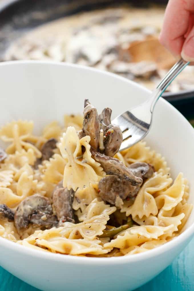 Portobello Mushroom Pasta with Cream Sauce in white bowl being picked by fork