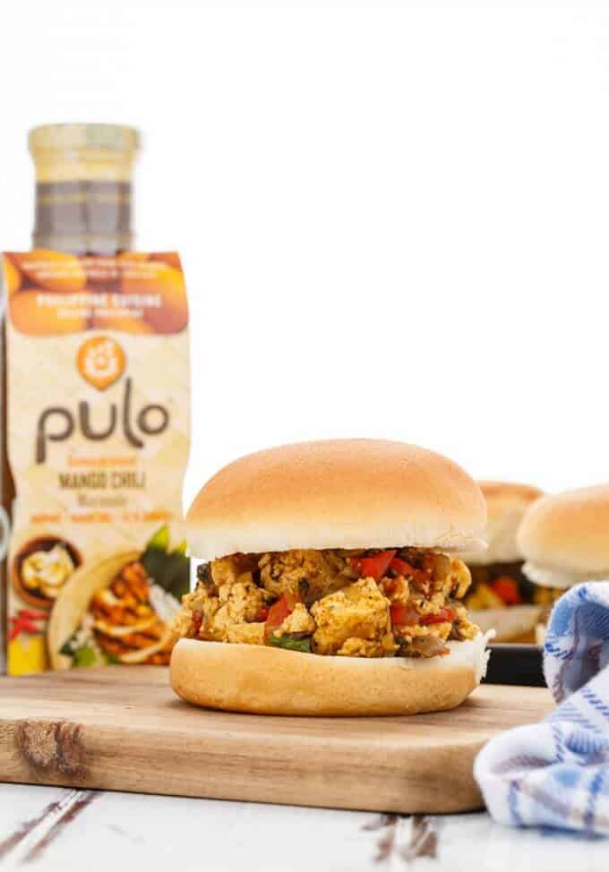 Pulo Mango Chili Vegan Sloppy Joes as burger on wooden pad, pulo marinade in the background