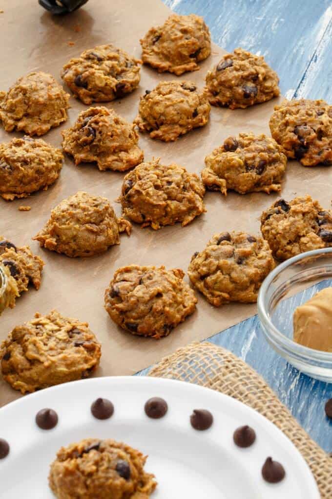 Sweet Potato Chocolate Chip Cookies on baking paper with glass bowl and plate with cookies