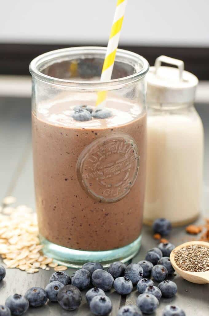 Almond Milk Banana-Blueberry Breakfast Smoothie in glass with strawon table next to blueberries, oats and jar of milk #smoothie