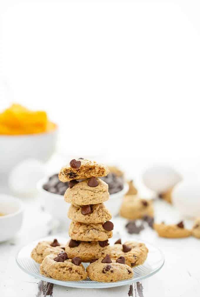 Chocolate Chip Pumpkin Cookies stacked on white plate, ingredients on background on table