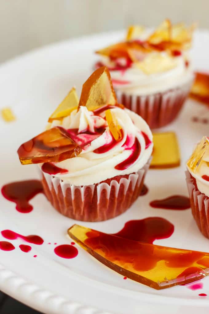 Halloween Cupcakes Blood Cupcakes with Broken Beer Bottle Glass Shards on white plate with drops of syrup and glass shards