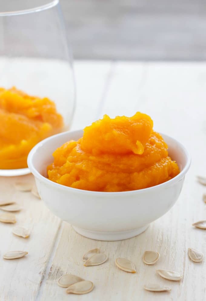 Homemade Pumpkin Puree in white bowl and glass jar on white table with pumpkin seeds#babyfood