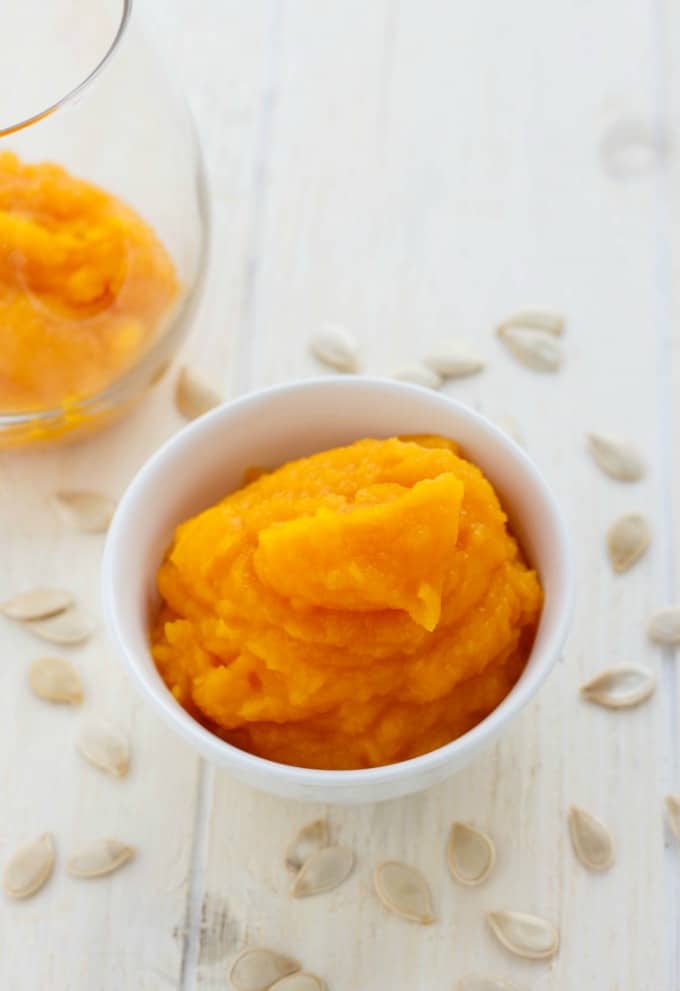 Homemade Pumpkin Puree in white bowl and glass jar on white table with pumpkin seeds #glutenfree