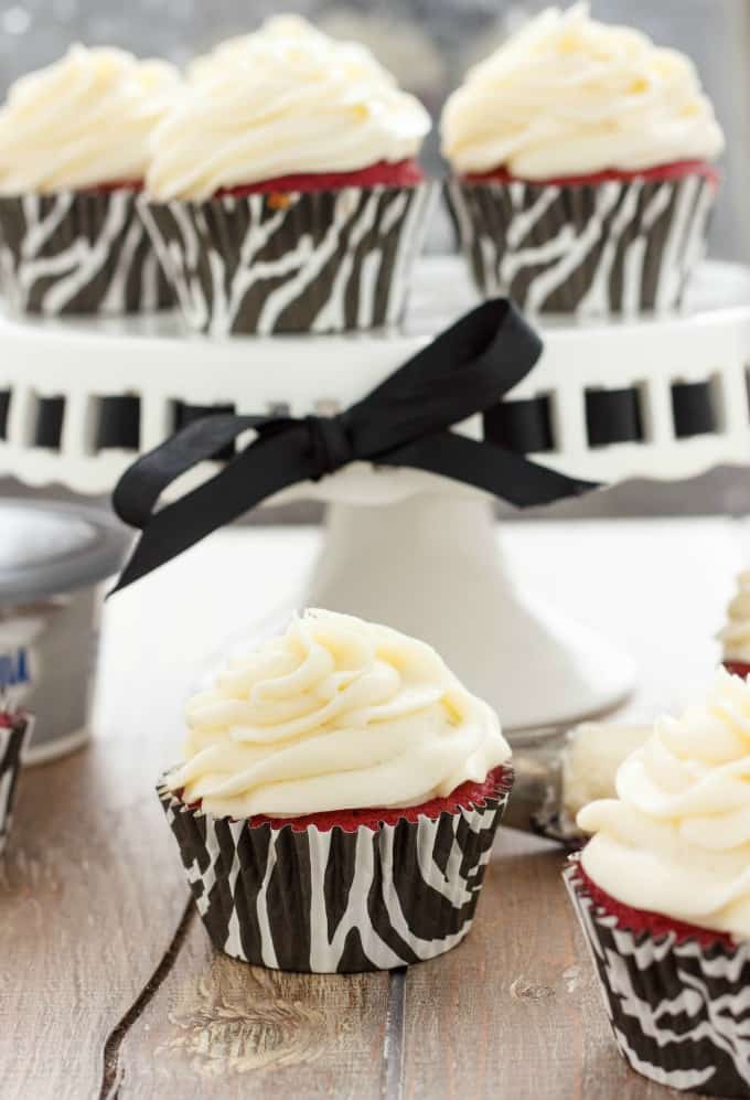 Red Velvet Cupcakes with Cream Cheese Frosting  on brown table, in the background cupcakes on white tray#redvelvet