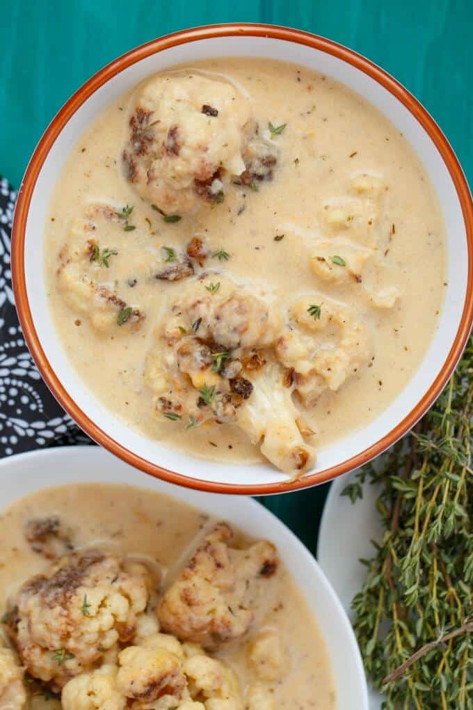 Roasted Cauliflower Soup in white bowls on blue table 