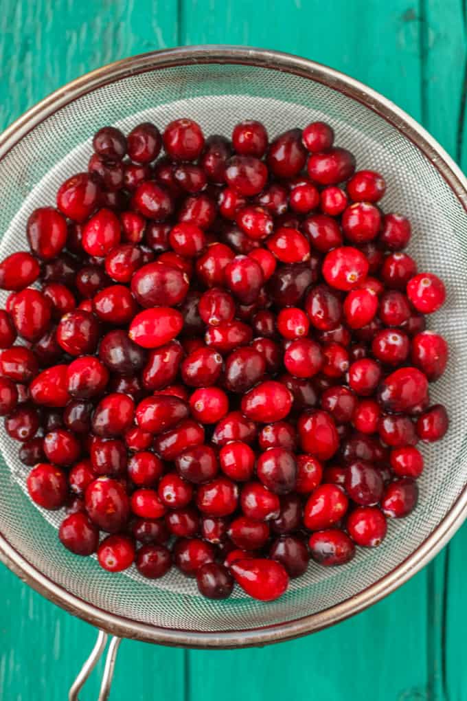 Strainer full of cranberries on blue table