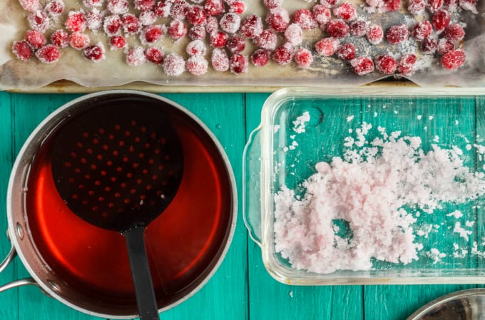 Candied Cranberries with Amaretto Liqueur in the making on blue table with glass container, potfop and candied cranberries