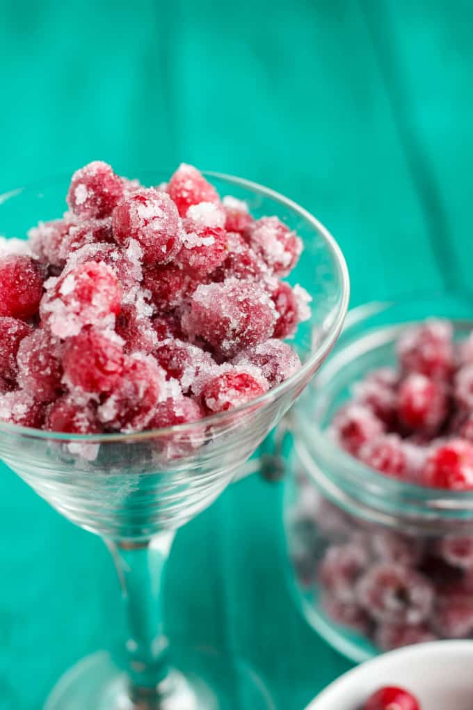 Candied Cranberries with Amaretto Liqueur in glass with jar of candied cranberries on blue table