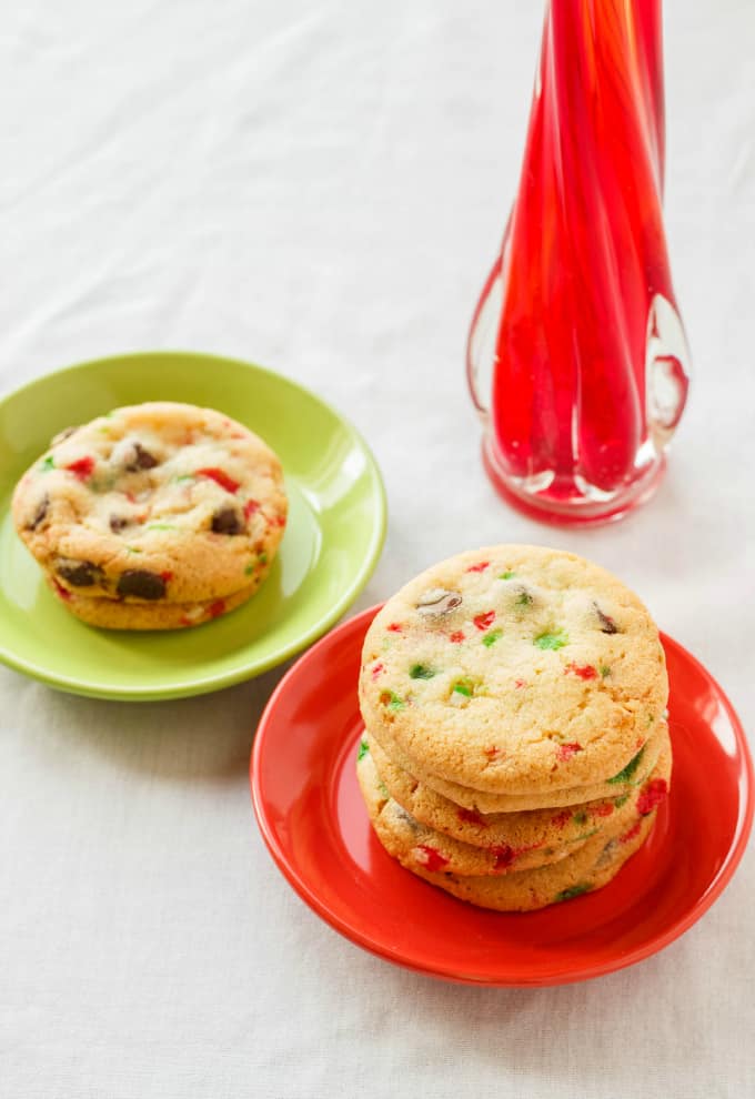 Crushed Candy Cane Chocolate Chip Cookies on red and green plate with candy cane on white table