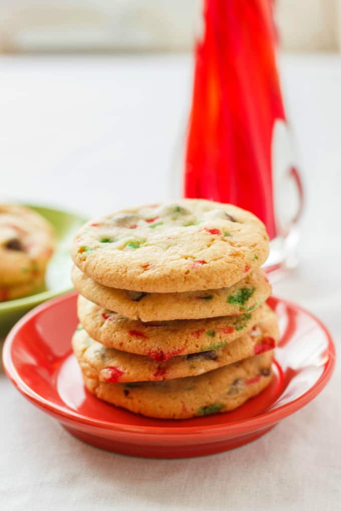 Crushed Candy Cane Chocolate Chip Cookies on red and green plate with candy cane on white table