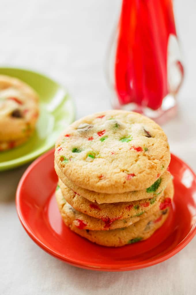 Crushed Candy Cane Chocolate Chip Cookies on red and green palte with candy cane on white table