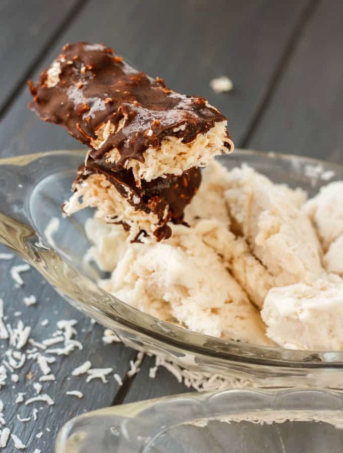 Vegan Toasted Coconut Ice Cream with chocolate frostin on glass tray on gray table with sliced coconut