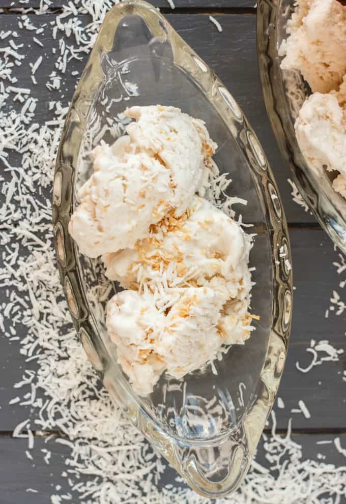 Vegan Toasted Coconut Ice Cream on glass tray on gray table with sliced coconut